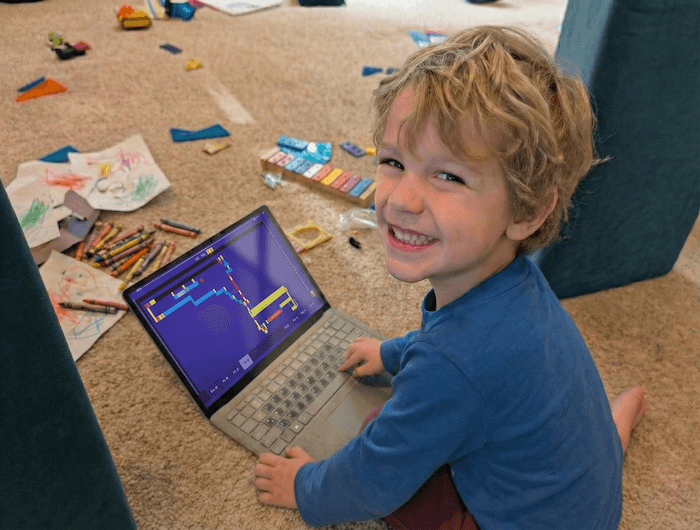 Child smiling near Purple Computer