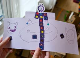 A paper creation a kid made for Purple: drawings with the letter stickers and the Purple bot on top